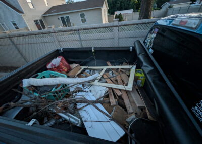 Pickup truck bed filled with debris and scrap wood in a residential backyard.