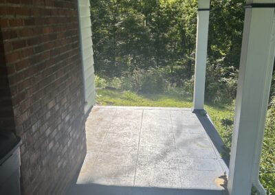 Covered porch with brick wall on the left, white columns and blue trim, opening to a green garden beyond.